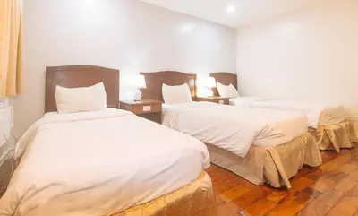 a hotel room with two beds with white sheets at Comfy Inn Manila Kalaw by RedDoorz in Manila