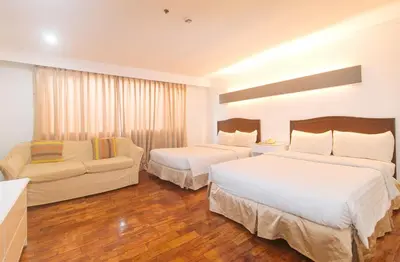 a hotel room with two beds and a couch at Comfy Inn Manila Kalaw by RedDoorz in Manila