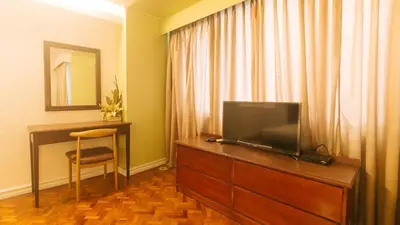 a hotel room with a television on a dresser with a desk at Comfy Inn Manila Kalaw by RedDoorz in Manila