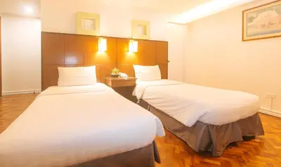 two beds in a hotel room with white sheets at Comfy Inn Manila Kalaw by RedDoorz in Manila