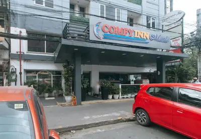 a red car parked in front of a building at Comfy Inn Manila Kalaw by RedDoorz in Manila