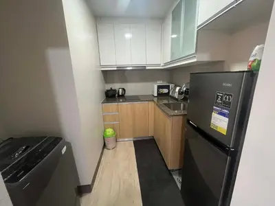 a small kitchen with a black refrigerator and wooden cabinets at Gentry Manor Family Room 2 Beds Near Okada MOA NAIA 8E in Manila