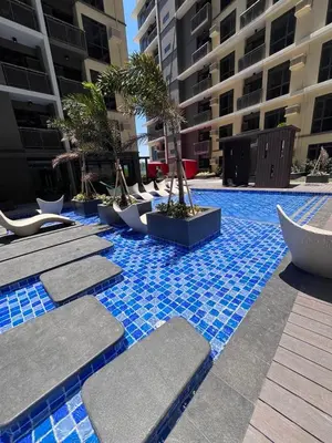 a pool with chairs and trees in a building at Gentry Manor Family Room 2 Beds Near Okada MOA NAIA 8E in Manila