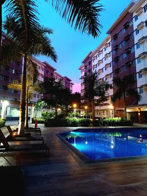 a hotel courtyard with a swimming pool at night at Kaunis Hive Hope Residences in Trece Martires