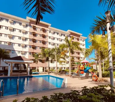 a hotel with a swimming pool and palm trees at Kaunis Hive Hope Residences in Trece Martires