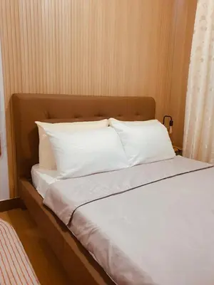 a bed with white sheets and pillows on it at Kaunis Hive Hope Residences in Trece Martires
