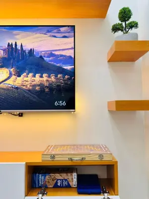 a tv hanging on a wall with a shelf at Claire's place in Manila