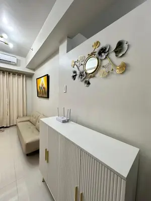 a white living room with a mirror on the wall at Claire's place in Manila