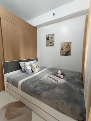 a large bed with a person laying on it at Stylish Condo with City View and Netflix - Pool Access in Manila