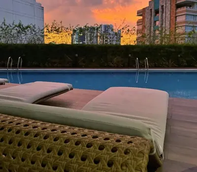 a bed sitting next to a pool with a sunset at Stylish Condo with City View and Netflix - Pool Access in Manila