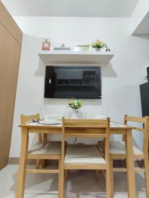 a dining room table and chairs with a television on a wall at Stylish Condo with City View and Netflix - Pool Access in Manila
