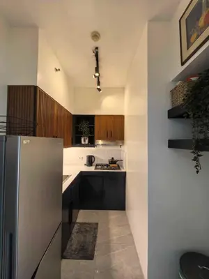 a kitchen with a stainless steel refrigerator and wooden cabinets at Chelsea Tower 1 in Manila