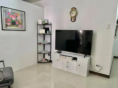 a living room with a television and a clock on the wall at A cozy condo within the center of Manila in Manila