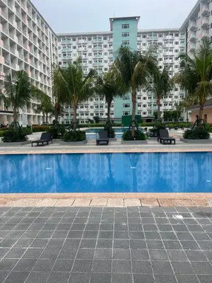 a swimming pool with palm trees and buildings at Field Residences Condominium in Manila