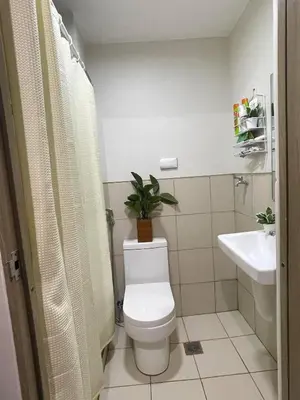 a bathroom with a toilet and a sink with a plant at Field Residences Condominium in Manila