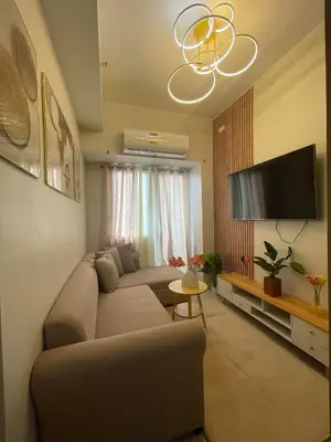 a living room with a couch and a flat screen tv at Field Residences Condominium in Manila