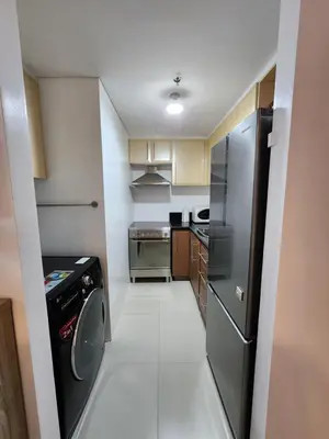 a small kitchen with a refrigerator and a dishwasher at 1BR Condo w Balcony near NAIA, Casino, Newport in Manila