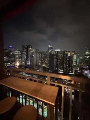 a view of a city skyline at night with a wooden bench at RED RESIDENCES Makati in Manila