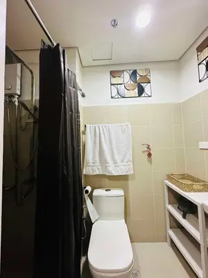 a bathroom with a white toilet and a shower at RED RESIDENCES Makati in Manila