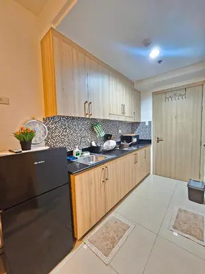 a kitchen with wooden cabinets and a black refrigerator at Tokyo Oasis at Shore 1 Residences Tower A, Pasay, MOA in Manila