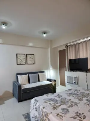 a living room with a bed and a couch at One Palm Tree Villas in Manila