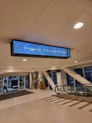 a sign in a shopping mall with a welcome to runway machine at One Palm Tree Villas in Manila