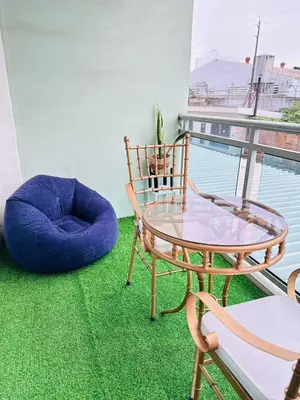 a balcony with a glass table and a chair and a ottoman at Paris Hilton Beach resort in Manila