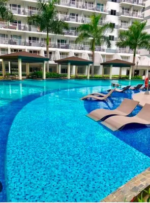 a swimming pool with lounge chairs and a large building at Executive Suite 519A at Shell Residence by GK Condotel in Manila
