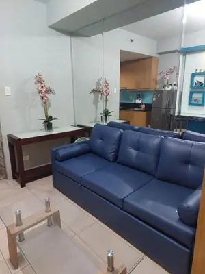 a living room with a blue couch and a kitchen at Suite 1443D at Shell Residence by GK Condotel in Manila