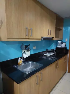 a kitchen with a sink and wooden cabinets at Suite 1443D at Shell Residence by GK Condotel in Manila