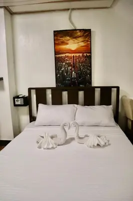 a bed with white sheets and a picture on the wall at furutech hostel in Manila