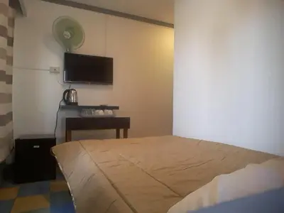 a bedroom with a bed and a desk and a flat screen tv at furutech hostel in Manila