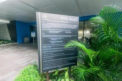 a sign in front of a building with plants at Cozy Crash Pad B Laughter friendly Makati 2271 Gym Swim Park 300 in Manila