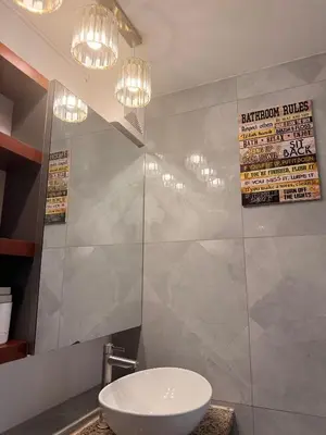 a bathroom with a toilet and two chandeliers at Cozy CondoVibe 2 BR Staycation near SM East Ortigas with Netflix! in Manila