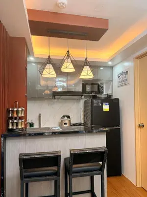 a kitchen with two bar stools and a refrigerator at Cozy CondoVibe 2 BR Staycation near SM East Ortigas with Netflix! in Manila