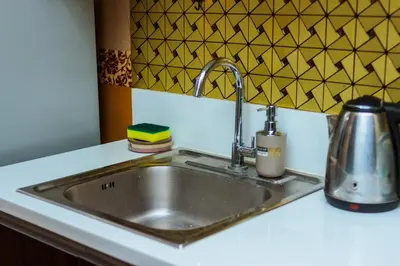 a stainless steel sink in a kitchen with a tea kettle at Secret Makati Love Haven Swim Gym Park Laugh 300MB in Manila