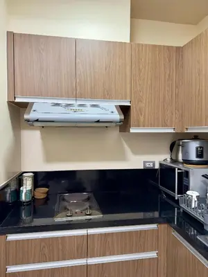 a kitchen with wooden cabinets and a stove top oven at BayFront 1BR Condo in Pasay with FREE Wi-Fi, Netflix, Pool Access & Gym, Near NAIA Airport, MOA, OKADA, CCP & PICC in Manila