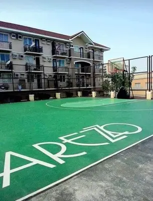a green basketball court in front of a building at Cozy 1 Bedroom Unit Arezzo Place Pasig in Pasig