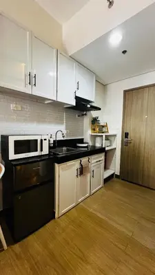 a kitchen with white cabinets and a black counter top at CityZen Suite in Trece Martires
