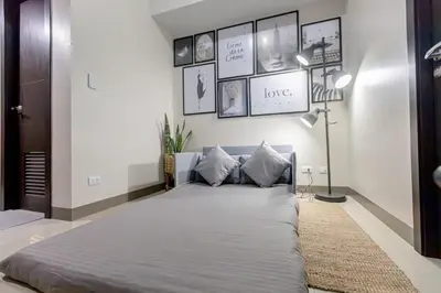 a large bed in a room with pictures on the wall at LUXX Suites McKinley with fast WIFI in BGC in Manila