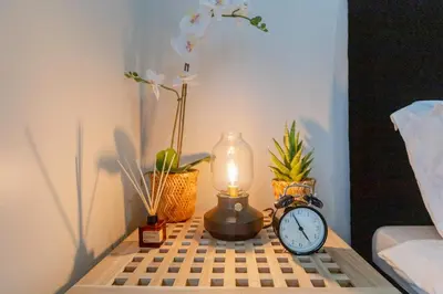 a table with a clock and a lamp and plants at LUXX Suites McKinley with fast WIFI in BGC in Manila