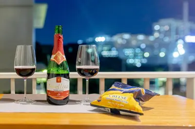 a bottle of wine and two glasses on a table at LUXX Suites McKinley with fast WIFI in BGC in Manila