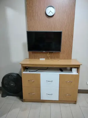 a entertainment center with a television and a clock on a wall at Room Near Naia Terminal 3 and New World Resort in Manila