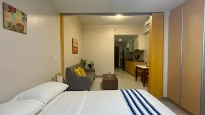 a bedroom with a bed and a living room at Full-Serviced Residential Apartment in One Uptown Residences, BGC in Manila