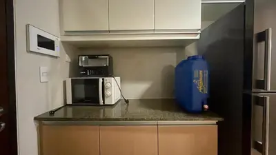 a kitchen with a microwave and a blue vase at Full-Serviced Residential Apartment in One Uptown Residences, BGC in Manila