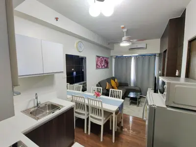 a kitchen and living room with a sink and a table at Stunning 2BR Condo in AIR Residences Makati High Floor and WFH with 300Mbps Wifi in Manila
