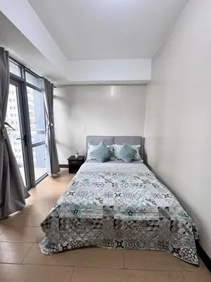 a bedroom with a bed and a large window at 2 Bedroom with Balcony in Manila