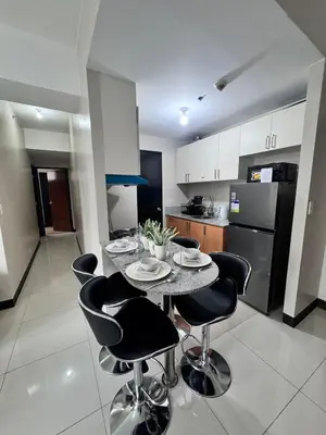 a kitchen with a table and chairs in a kitchen at 2 Bedroom with Balcony in Manila