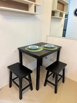 a table with two stools and a table with plates on it at Jazz Residences Tower B in Manila