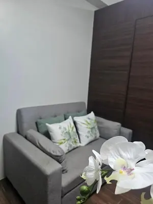 a gray couch with white flowers on a table at Air Residences Makati Sage Haven in Manila
